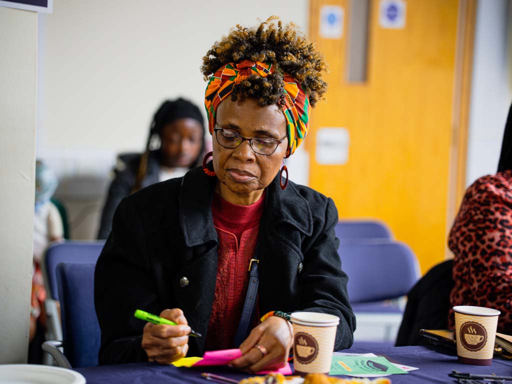 A woman at a community event writing ideas on paper